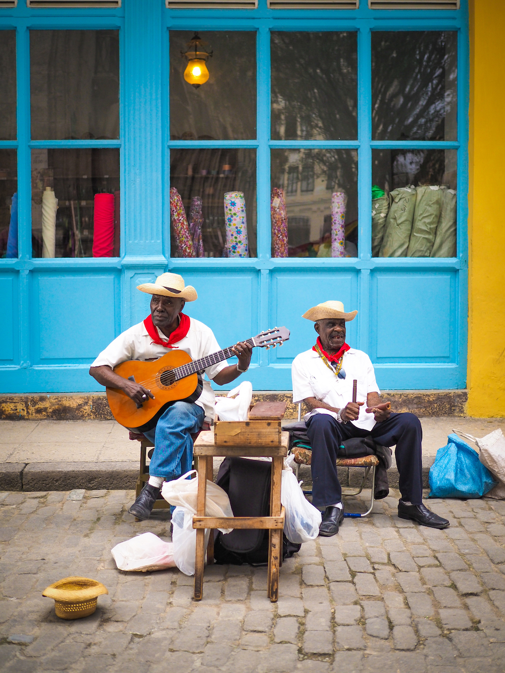 to gatemusikanter foran en turkis vegg på gaten i Havanna